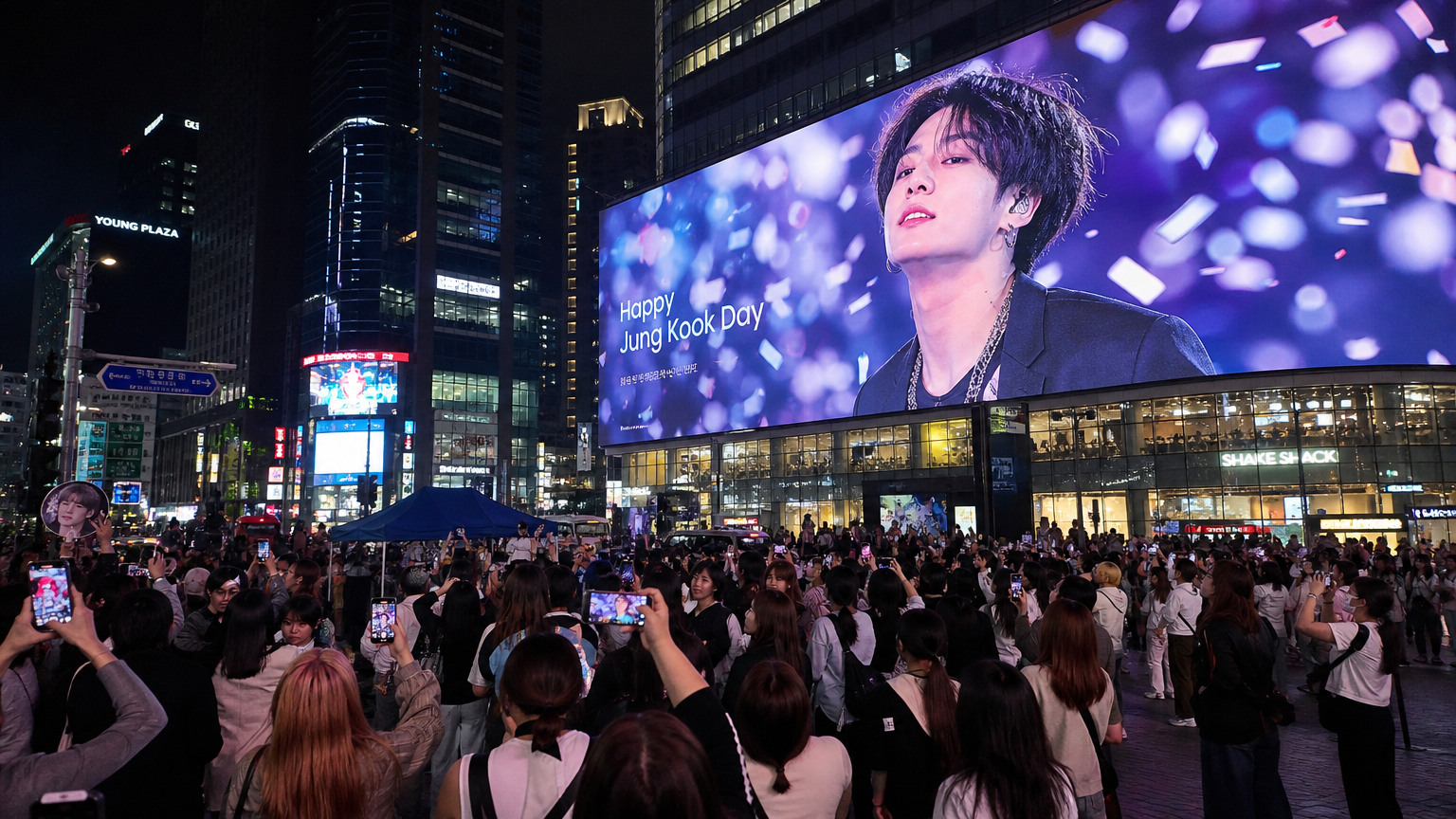 서울 번화가에서 인기 있는 한국 가수가 담긴 대형 LED 광고판과 그 주위에 모여든 열광적인 팬들