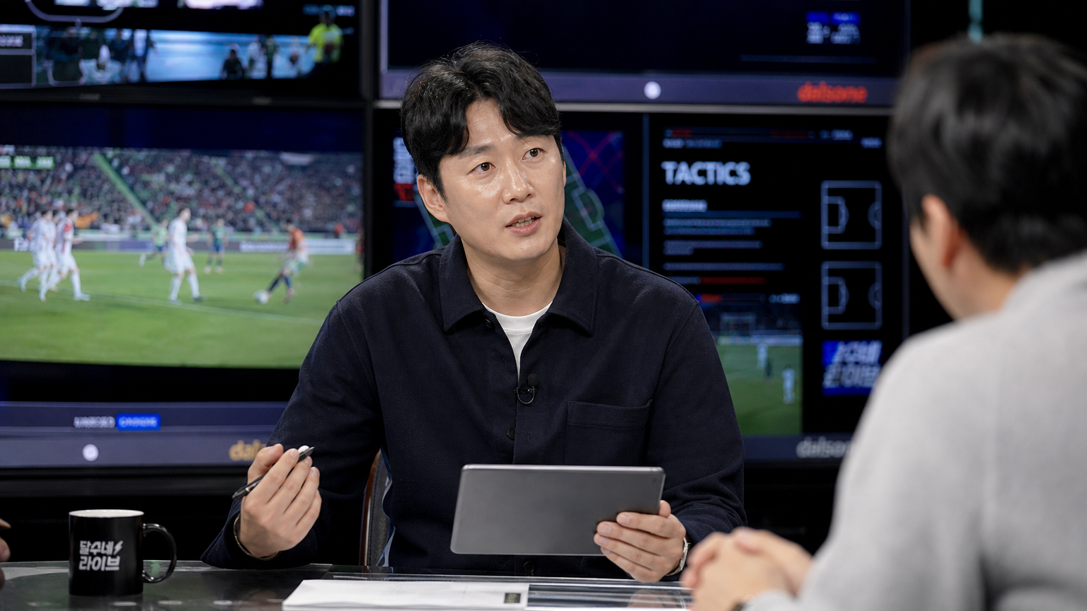 스포츠 클립이 보여지는 TV 세트에서 태블릿을 들고 전략을 논의하는 남성