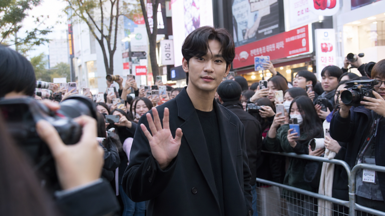 서울의 번화한 거리에서 팬들과 미디어에 둘러싸인 현대 한국 배우