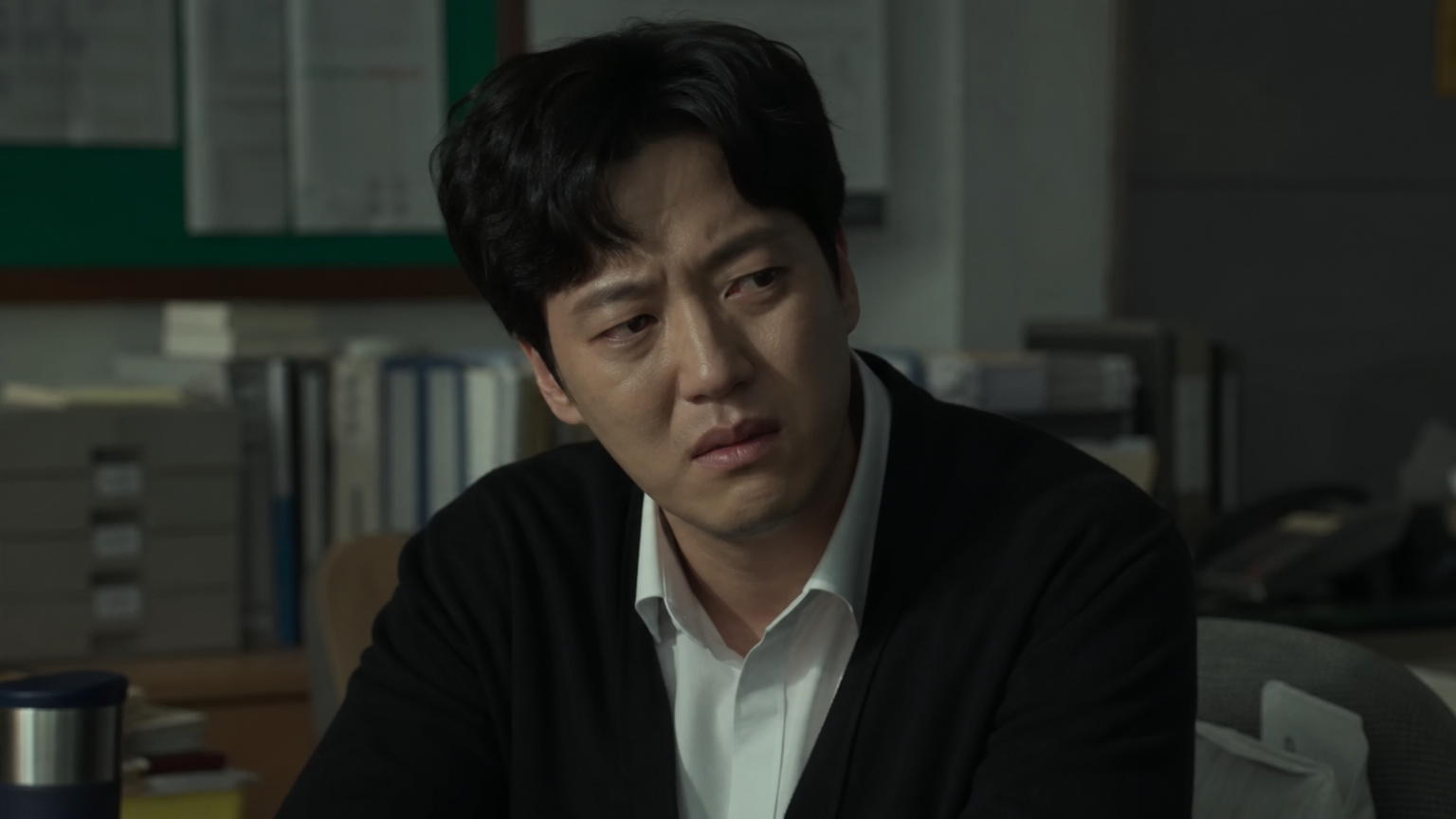 어두운 사무실에서 감정적 동요를 겪고 있는 교사 역의 배우 모습