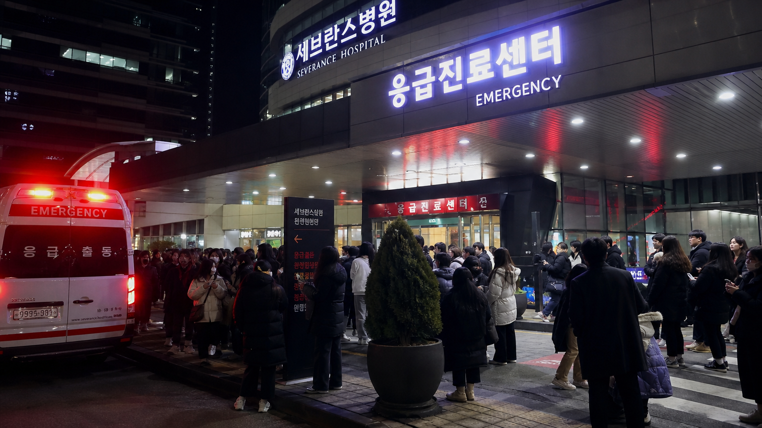병원 외부에 긴급 불빛이 번쩍이고 팬들이 모여 있는 모습