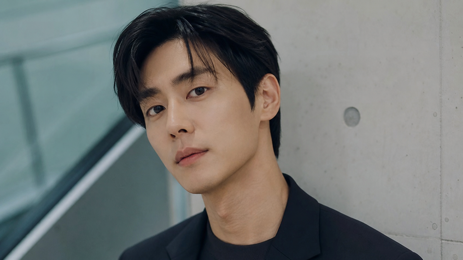 세련된 옷차림과 함께 깊이 있는 눈빛을 가진 젊어 보이는 배우