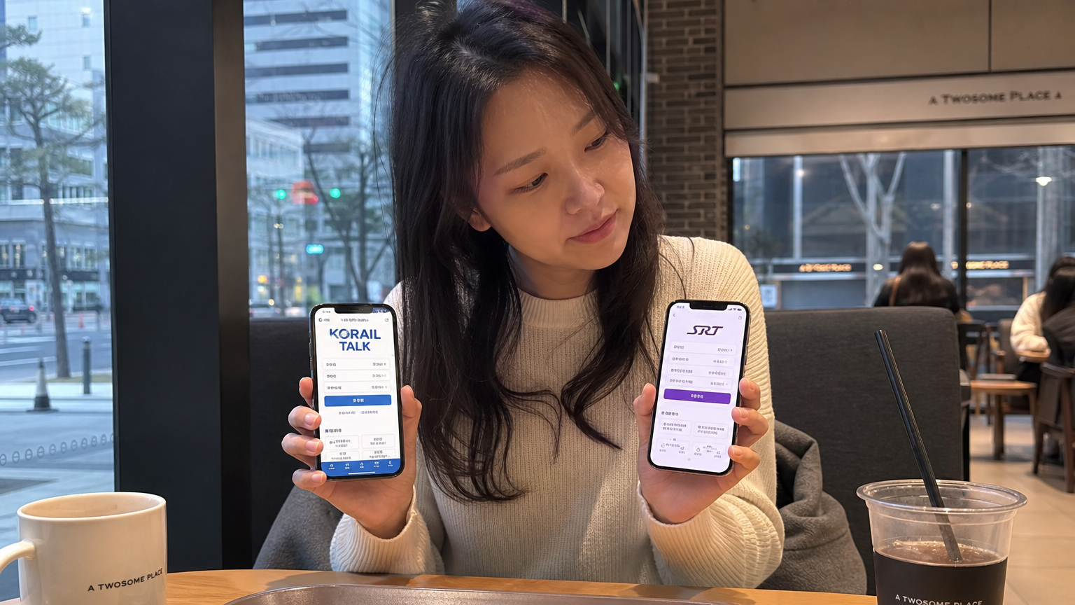 카페 테이블에서 두 스마트폰으로 코레일톡과 SRT 앱을 비교하는 여성