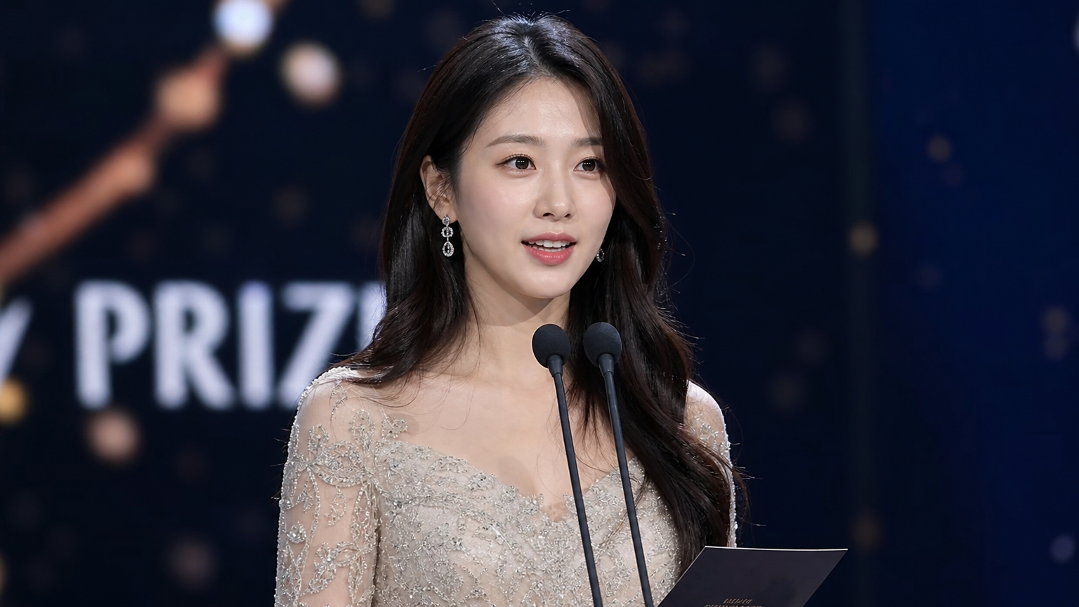 무대 조명을 배경으로 자신감 있게 연설하는 젊은 한국 여성