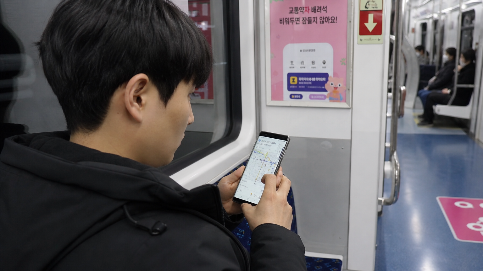 지하철 안에서 스마트폰으로 네비게이션 앱을 확인하는 한국 남성