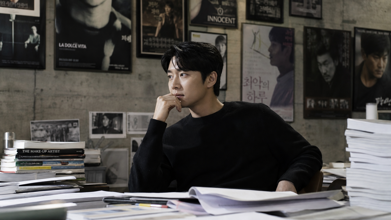 현대적인 스튜디오에서 영화 대본과 포스터로 둘러싸인 배우의 사색하는 모습