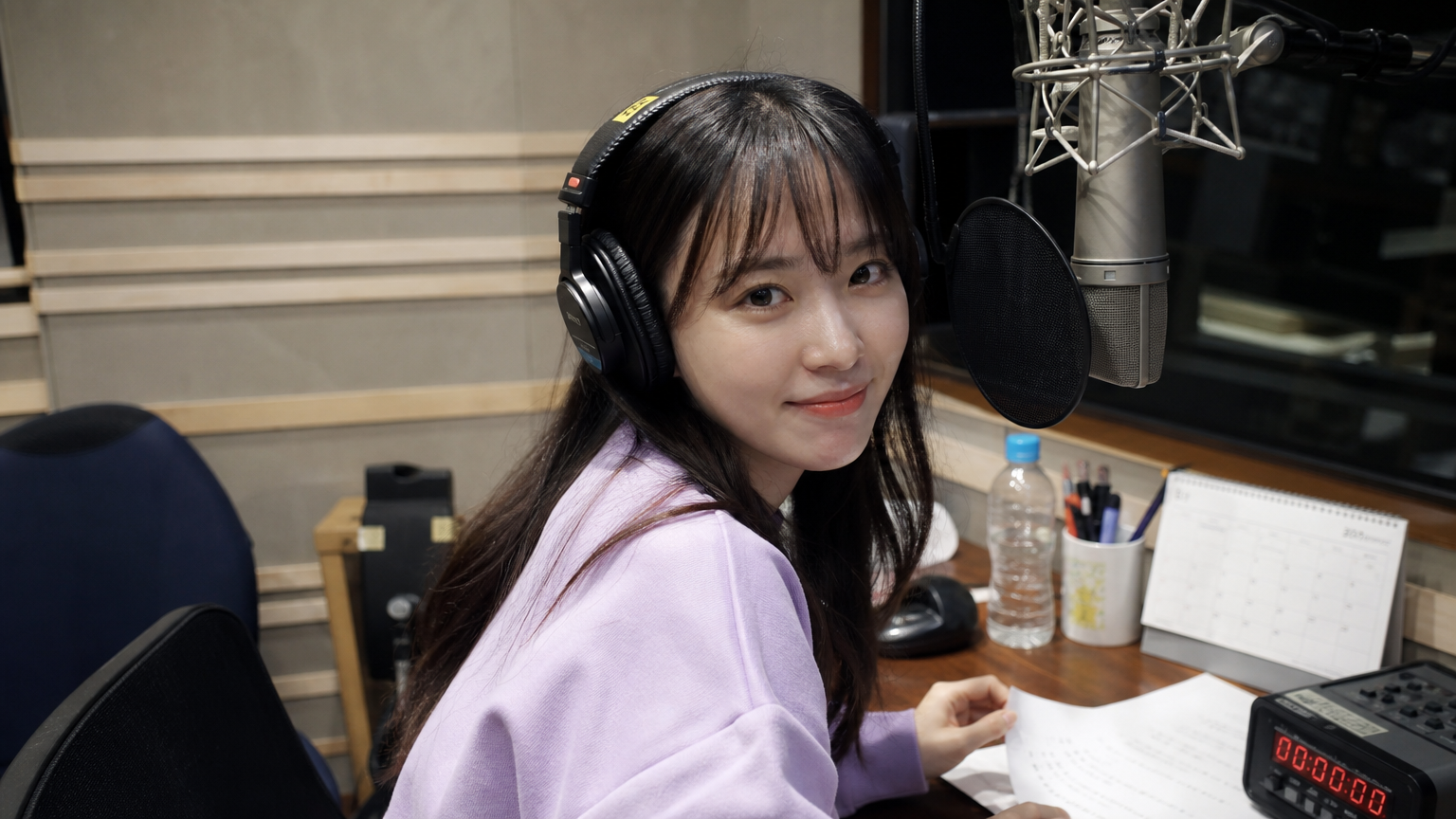 녹음실에서 헤드폰과 마이크를 사용하는 한국 성우의 모습
