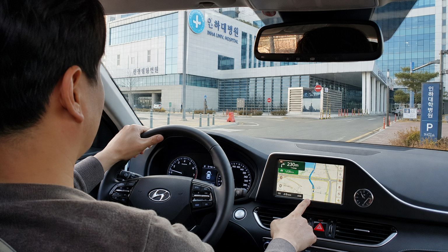인천의 현대식 병원을 향해 GPS 내비게이션 시스템을 사용하는 한국 운전자의 모습