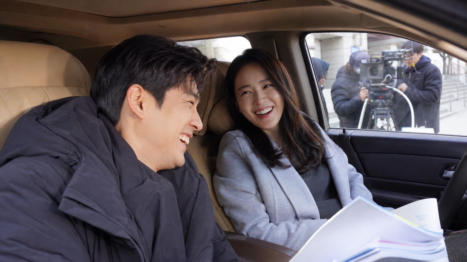 촬영 중 쉬는 시간에 차 안에서 함께 웃고 있는 두 명의 한국 연예인