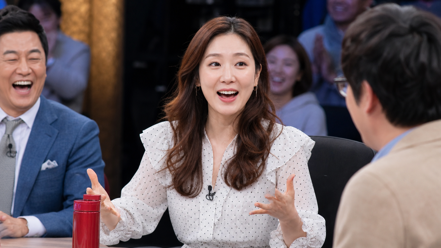 토크쇼에서 유머러스한 이야기를 전하며 관객들과 출연진을 웃게 만드는 장면