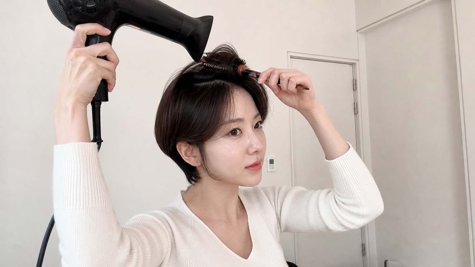 집에서 볼륨을 살리며 짧은 머리를 드라이하는 여성의 모습