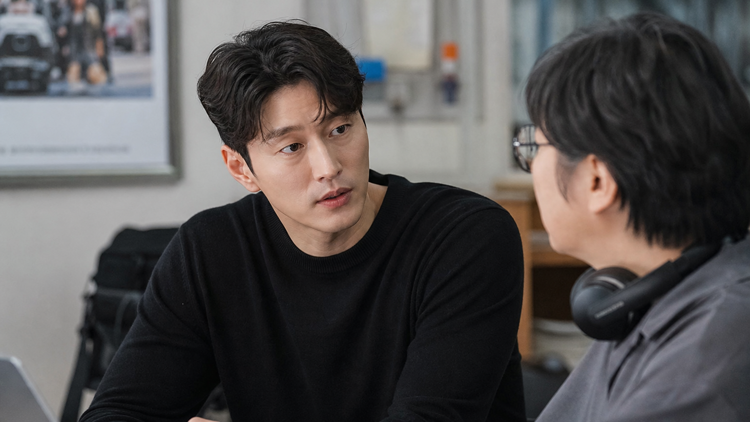 영화 세트장에서 감독과 대화 중인 현대적인 한국 남자 배우의 모습