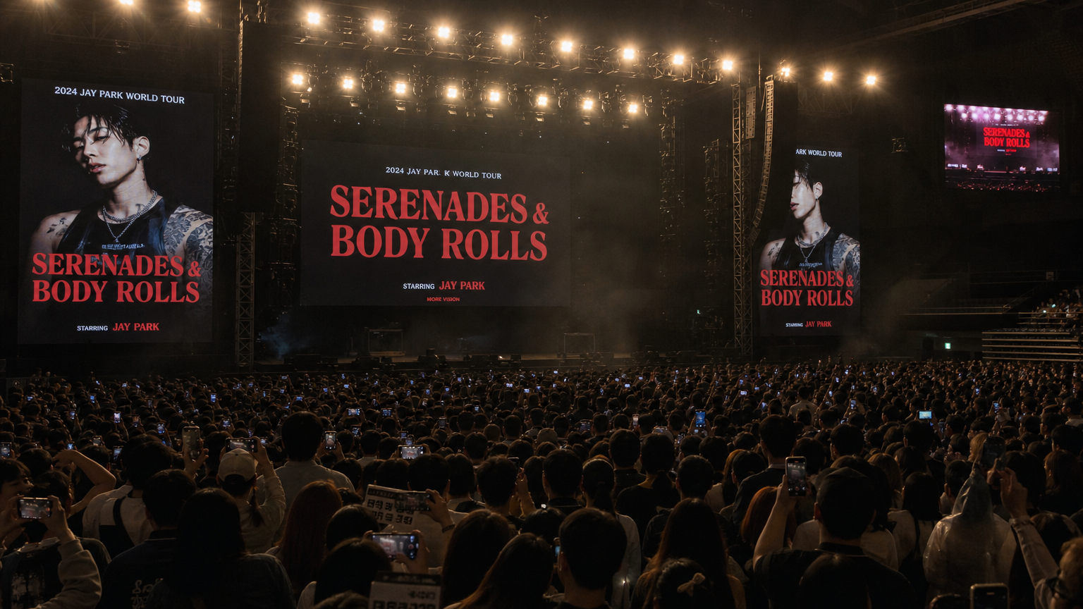 현대적인 콘서트 무대에서 큰 관중들이 제이 박의 '세레나데즈 앤 바디롤즈' 투어 포스터와 함께 열광하는 장면
