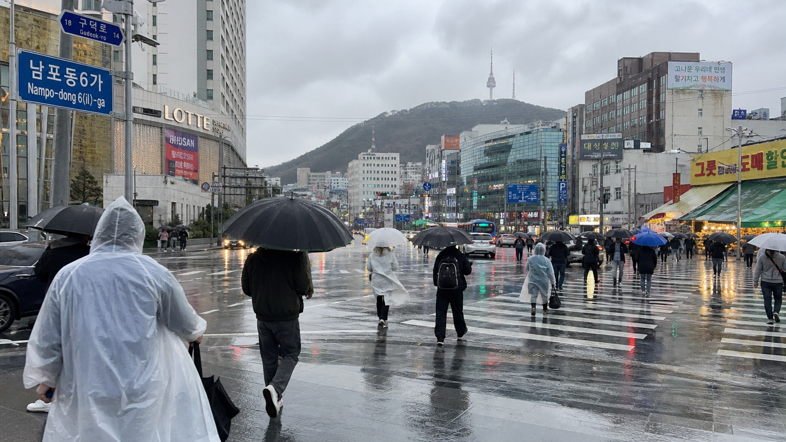 우산과 우비를 쓴 사람들이 있는 비 오는 부산 거리