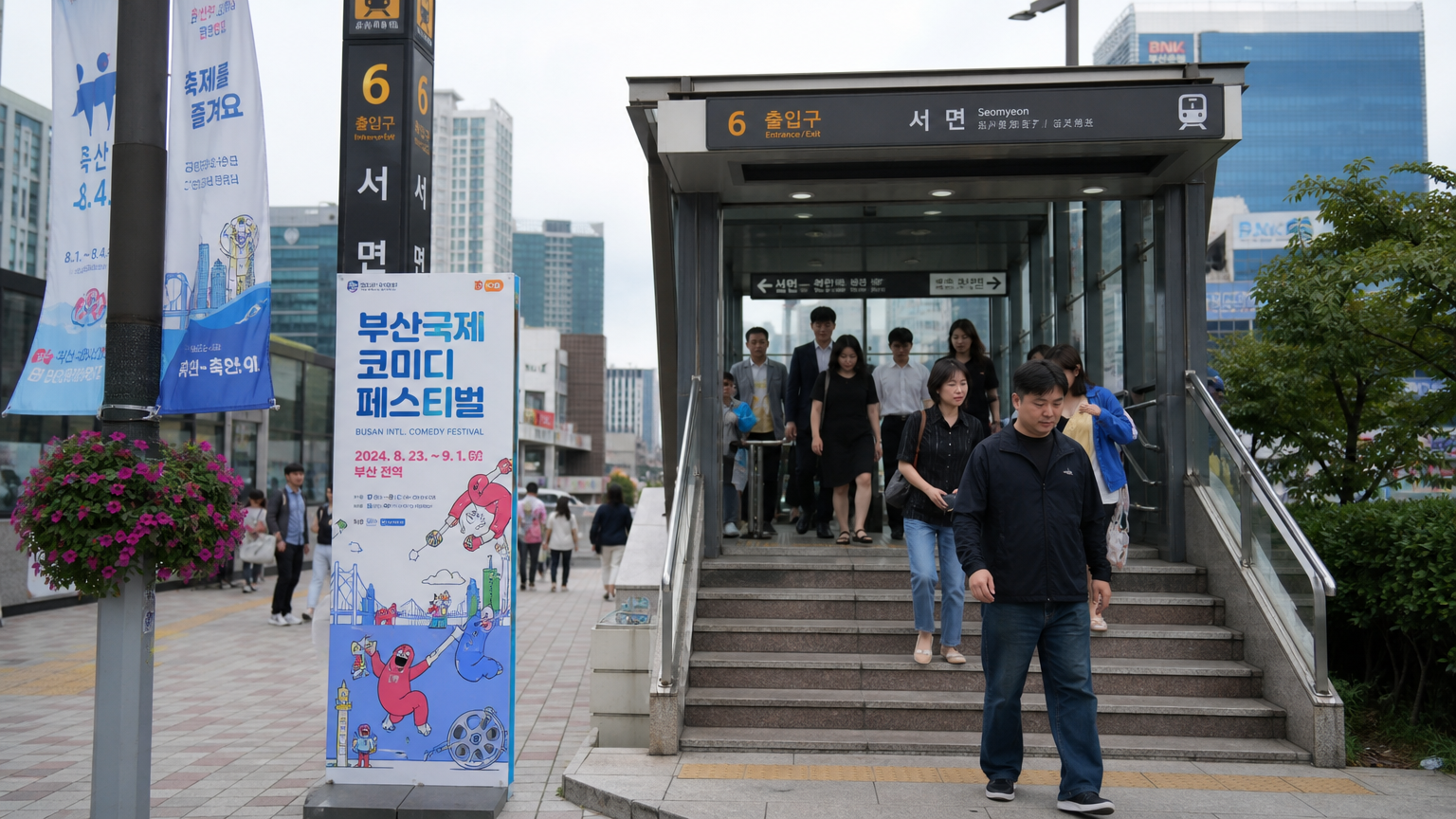 부산 도시철도 역 입구에서 나오는 성인들과 축제를 알리는 배너