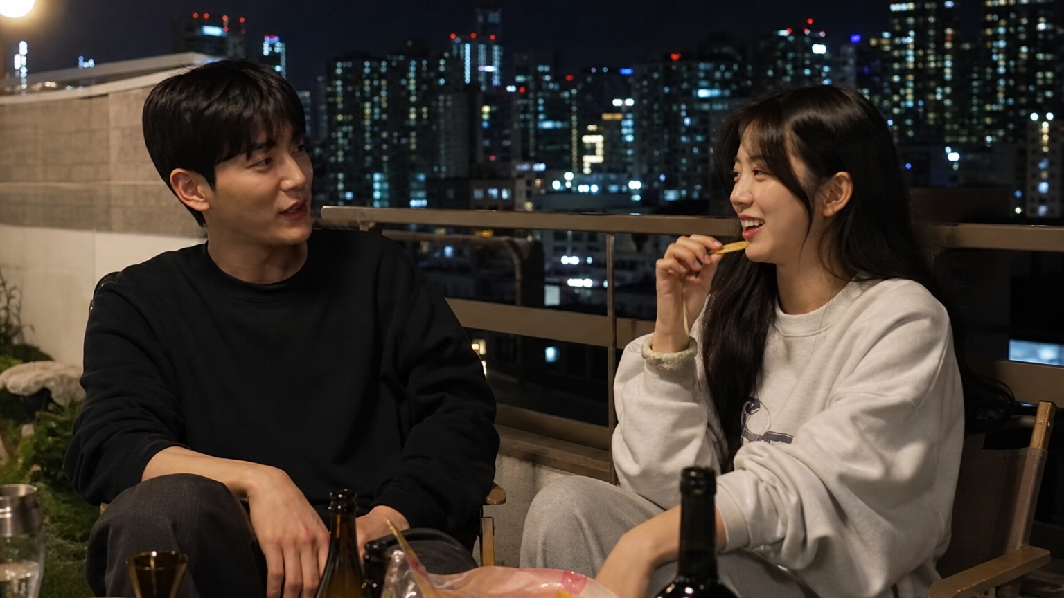 밤 도시 불빛 아래 발코니에서 편안하게 대화 나누는 한국 연예인들