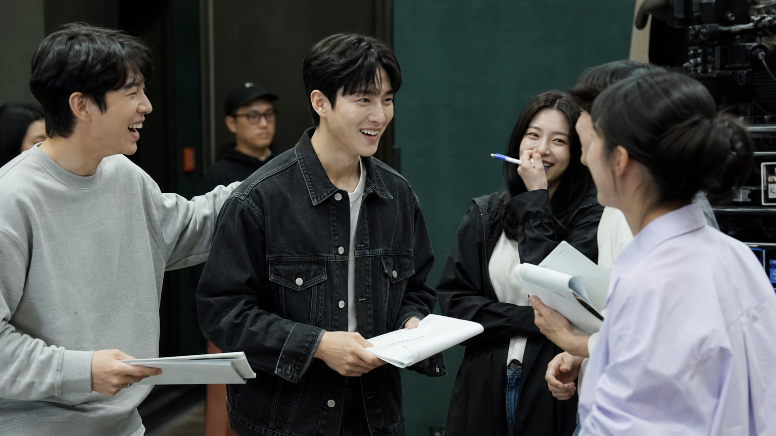 인기 드라마 세트장에서 새로운 배우가 기존 출연진과 함께 리허설에 참여하는 활기찬 모습