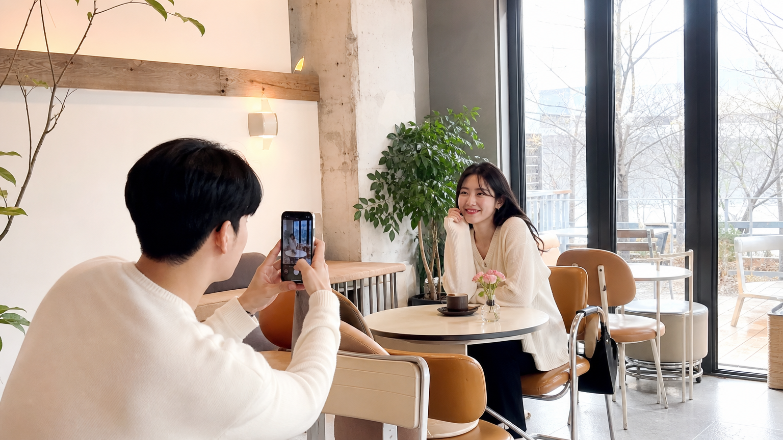 젊은 커플이 카페에서 서로 사진을 찍으며 즐기는 모습