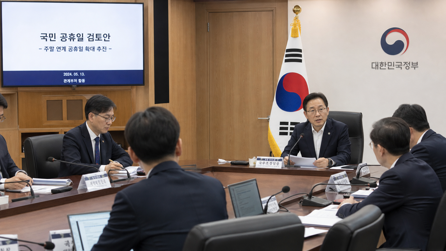한국 관료들이 큰 회의 테이블에서 공휴일 관련 논의를 진행하는 정부 회의실 내부 모습
