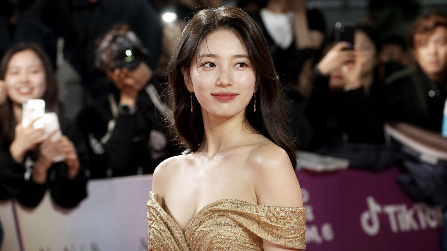금빛 오프숄더 드레스를 입고 시상식에서 주목받는 여배우의 모습