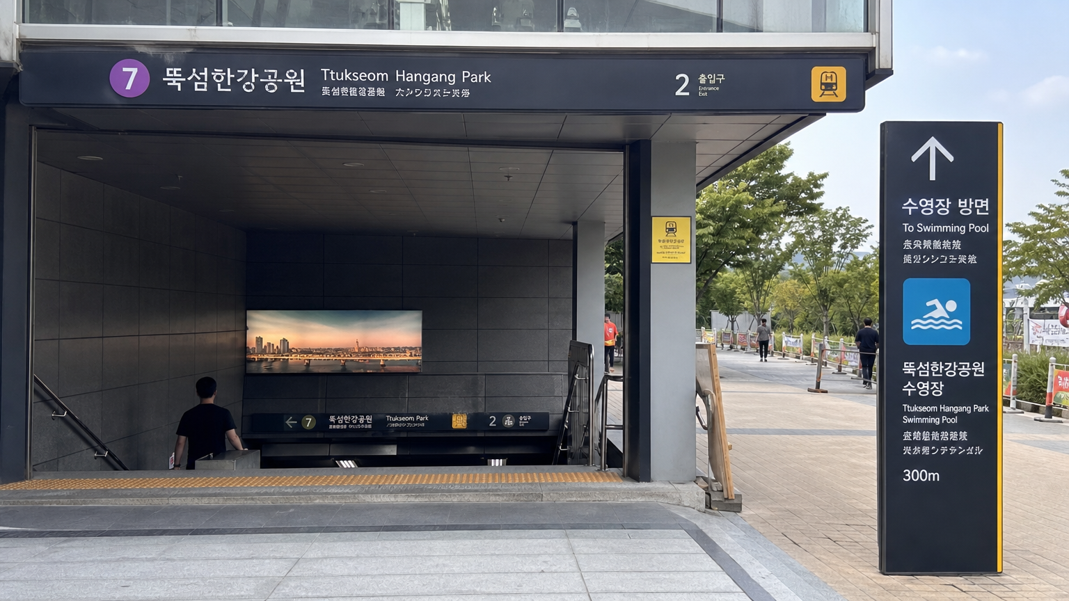 지하철 7호선 출구에서 뚝섬 한강공원 수영장으로 이어지는 안내 표지판과 주변 환경