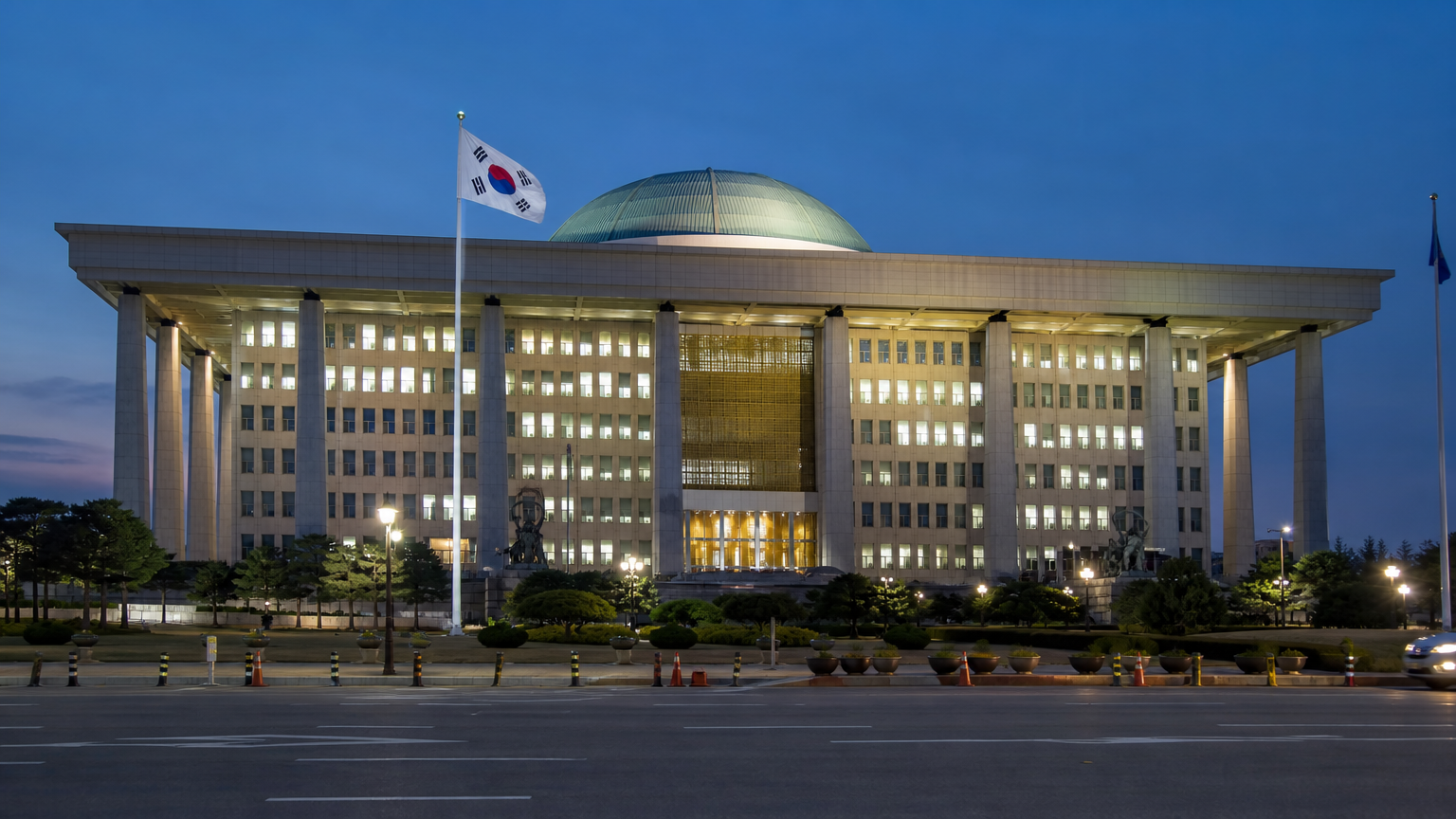 거리 조명 아래 한국 국기가 휘날리는 정부 청사의 외관