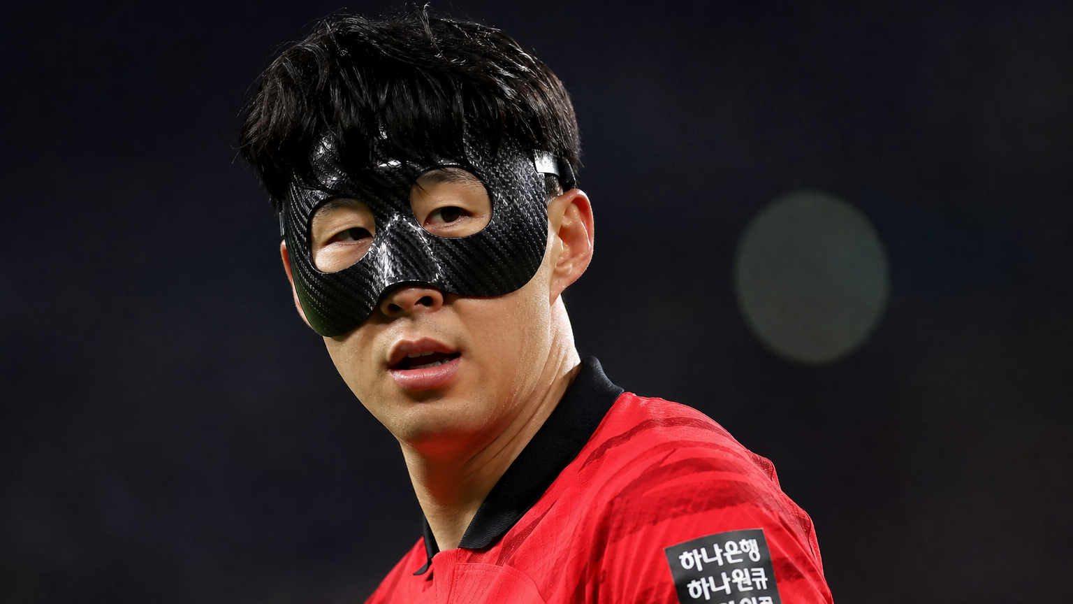 야간 경기장에서 보호 마스크를 착용한 한국 축구 선수의 클로즈업 모습