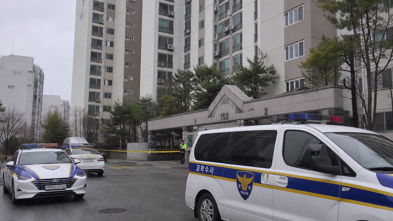 흐린 날 청주 아파트 입구에 경찰차와 폴리스 라인이 있는 장면