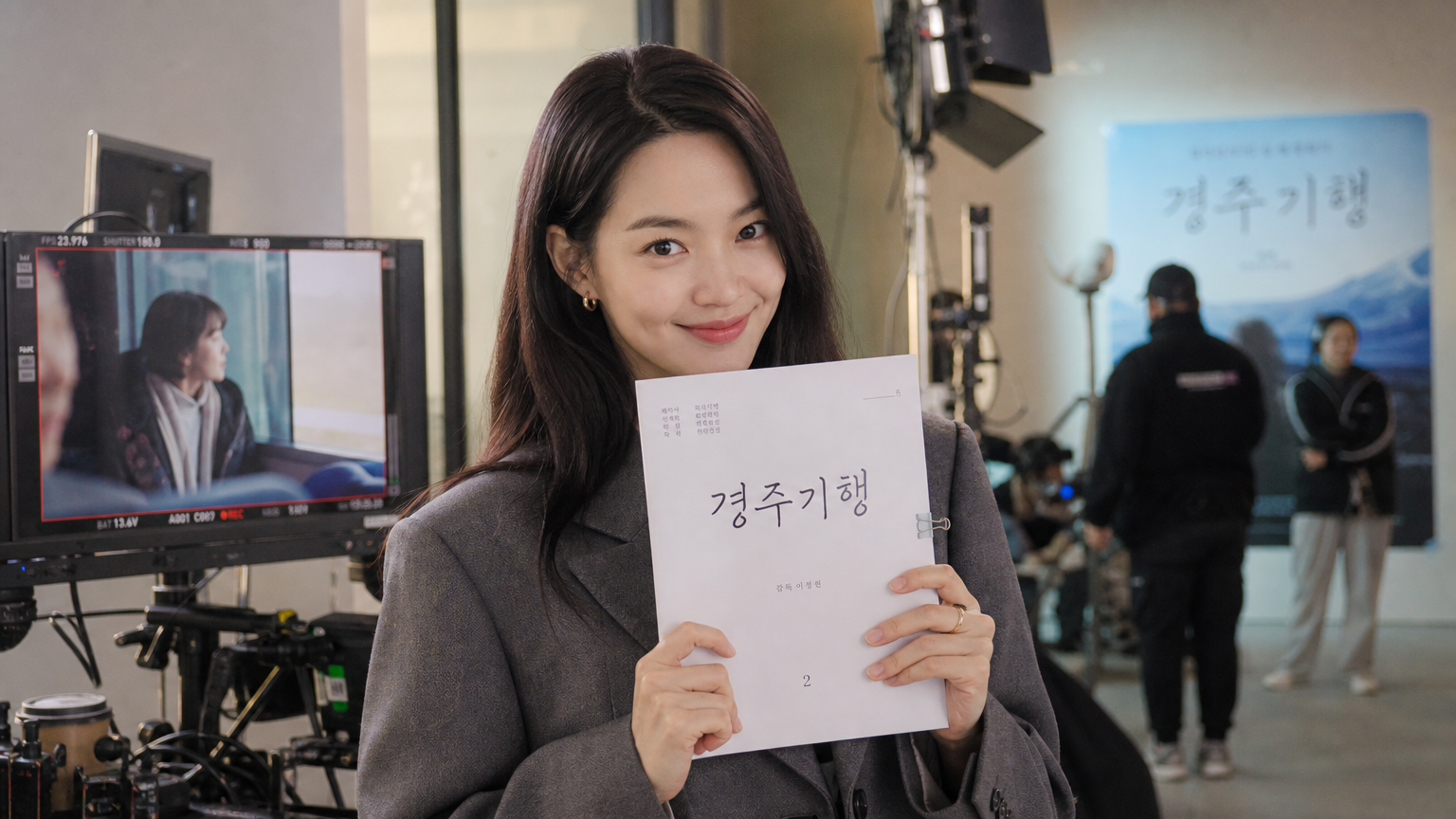 현대적인 영화 세트장에서 시나리오를 들고 있는 신민아 배우의 모습