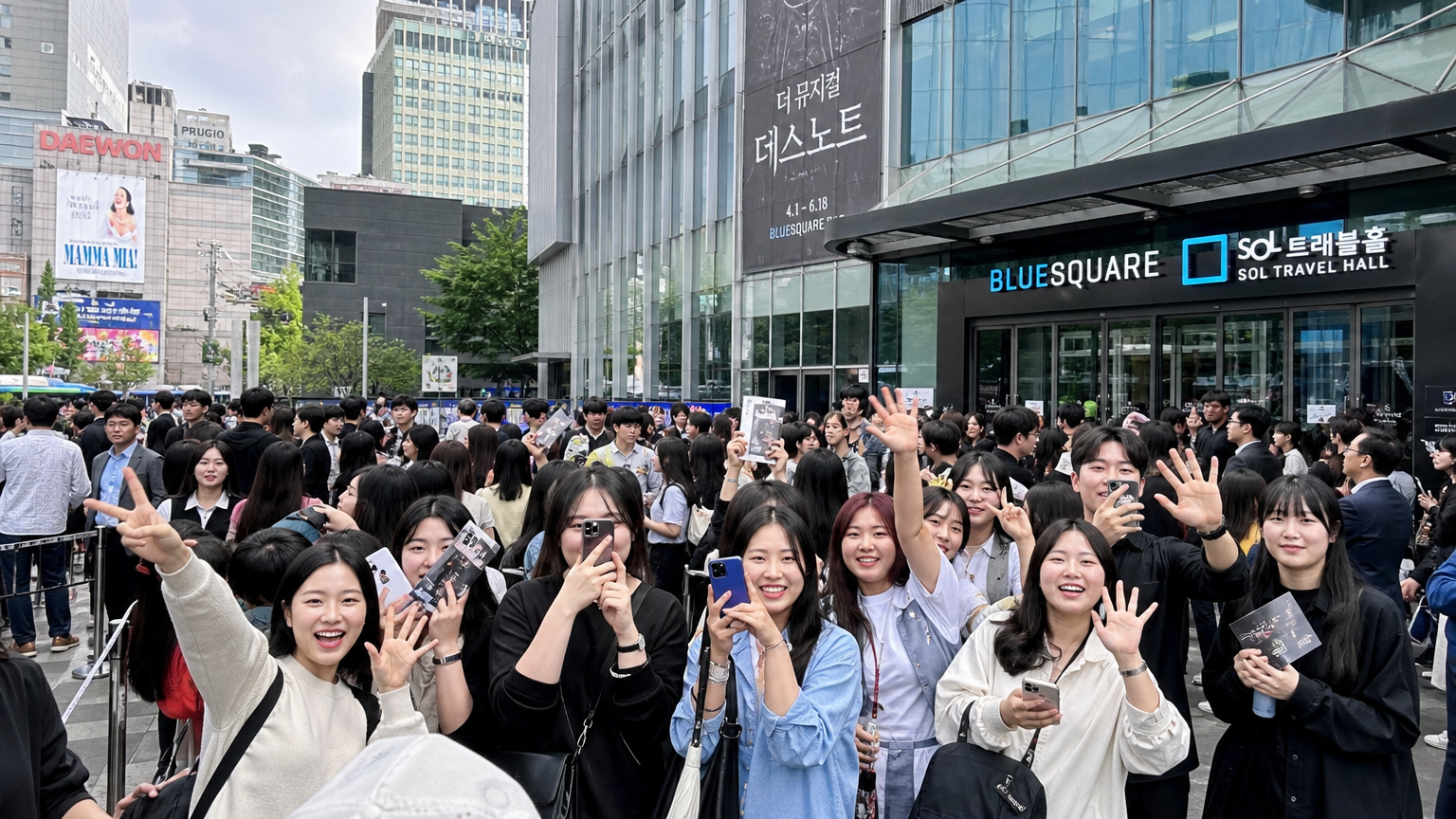 서울 블루스퀘어 극장 앞에서 설레는 표정의 현대적 한국 뮤지컬 팬들