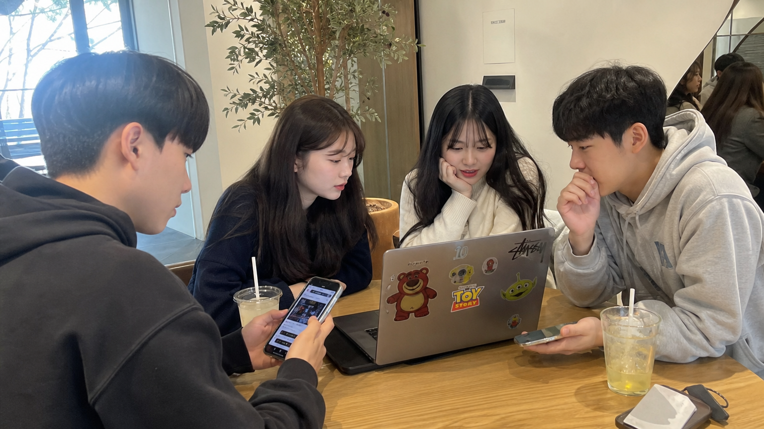 카페에서 스마트폰과 노트북으로 토이 스토리 관련 소문을 이야기하는 한국 청소년들