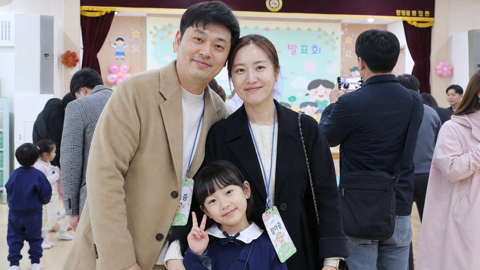학교 행사에 함께 참석하여 아이를 응원하는 부모의 모습