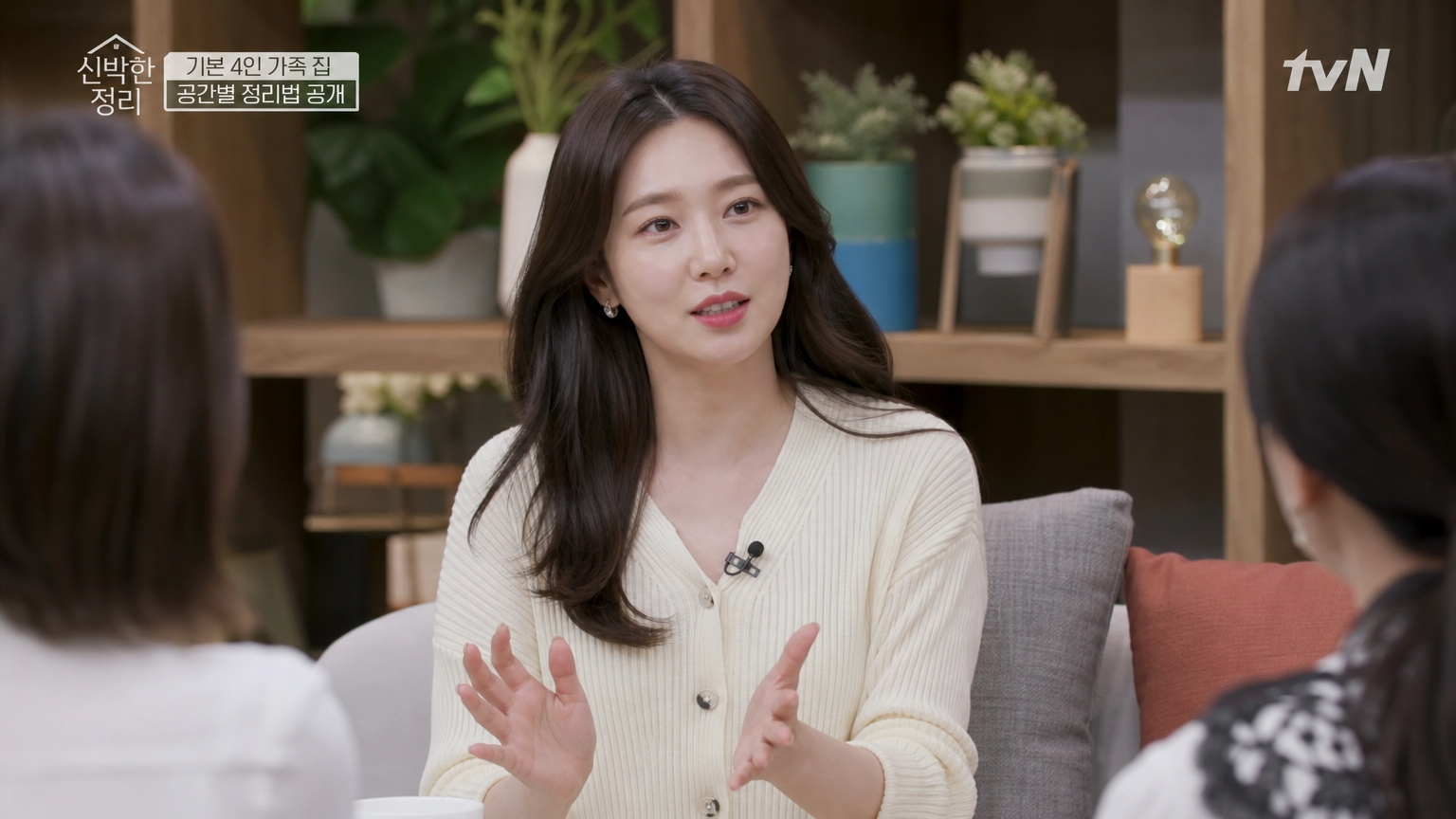 토크쇼 세트에서 공동 진행자들과 실용적인 생활 팁을 나누는 한국 여성