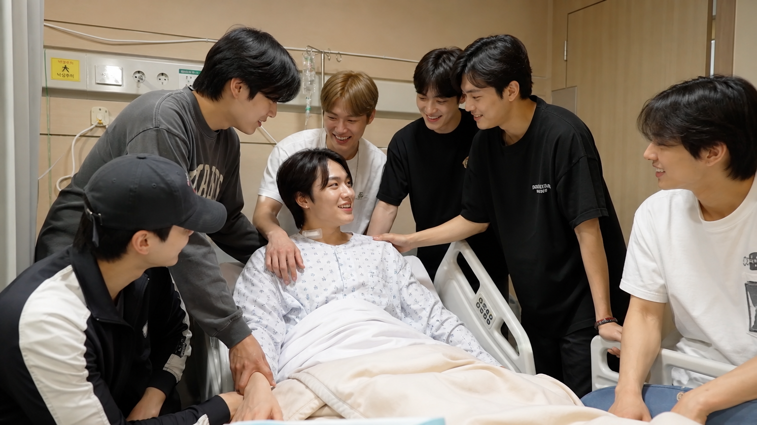 병원에서 회복 중인 한국 뮤지션을 둘러싼 친구들 그룹의 모습