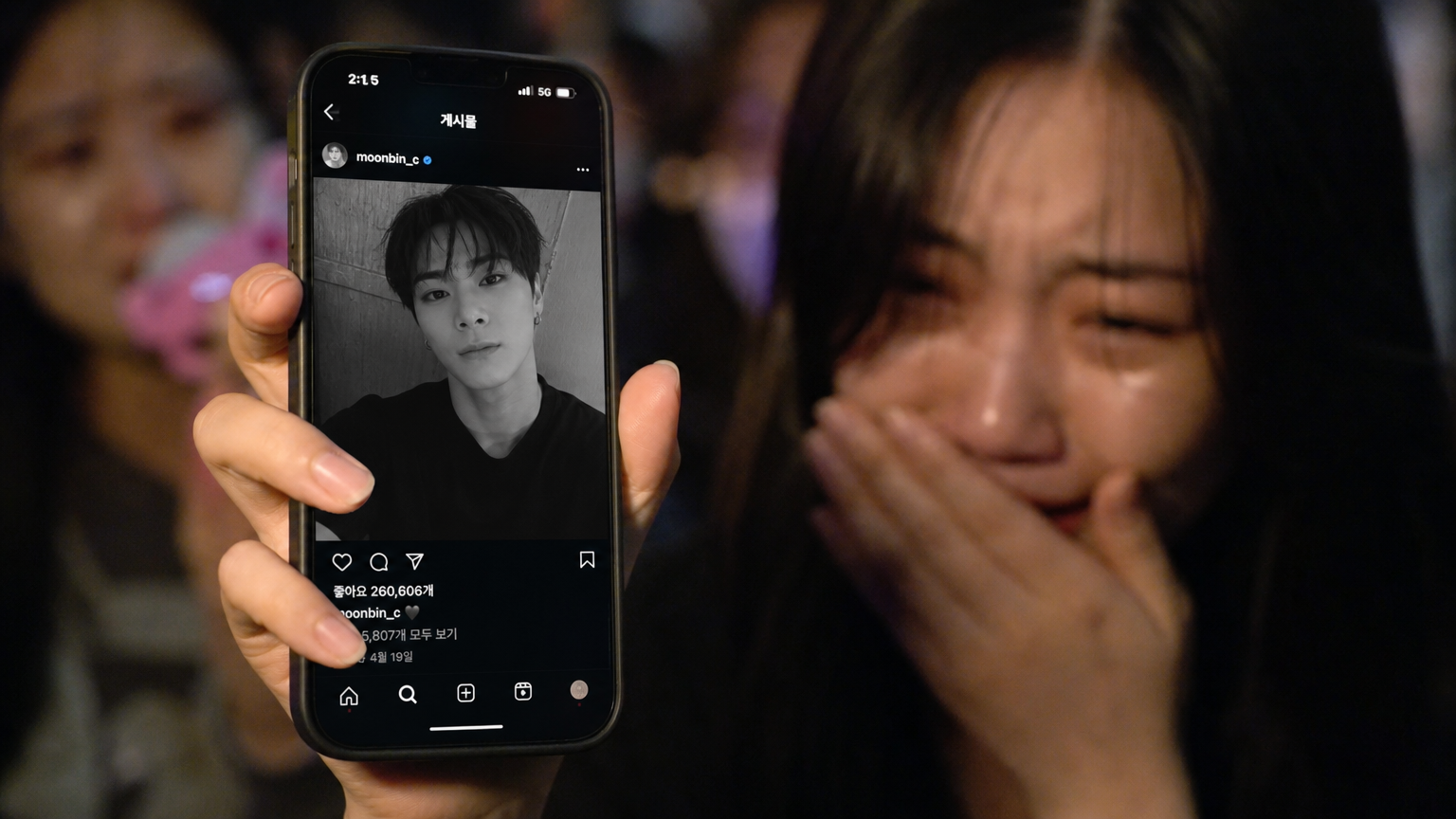 감정에 복받친 팬이 스마트폰 화면에서 보는 한국 가수의 마지막 SNS 게시물