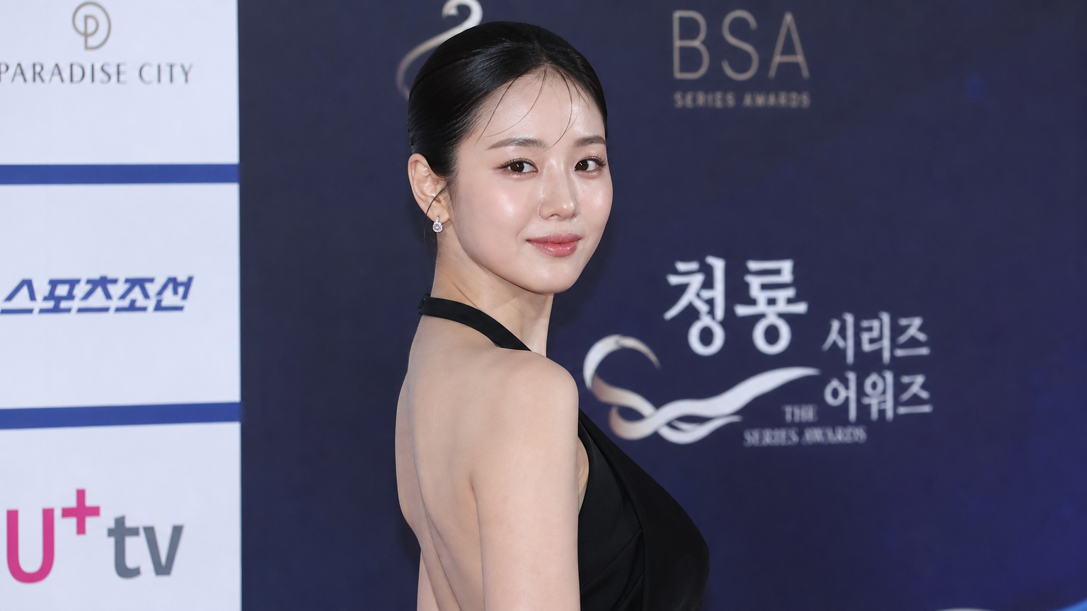 현대적인 매력을 발산하는 여배우가 청룡시리즈어워즈 레드카펫에서 올블랙 드레스와 슬릭백 헤어스타일로 등장한 모습