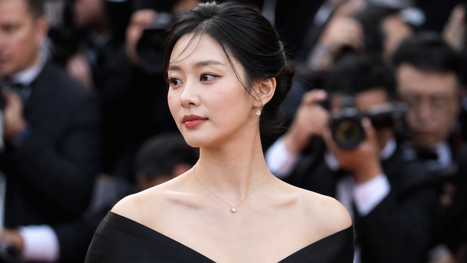 고급스럽고 세련된 주얼리를 착용하여 목과 어깨 라인을 돋보이게 한 여성이 올블랙 드레스를 입은 모습