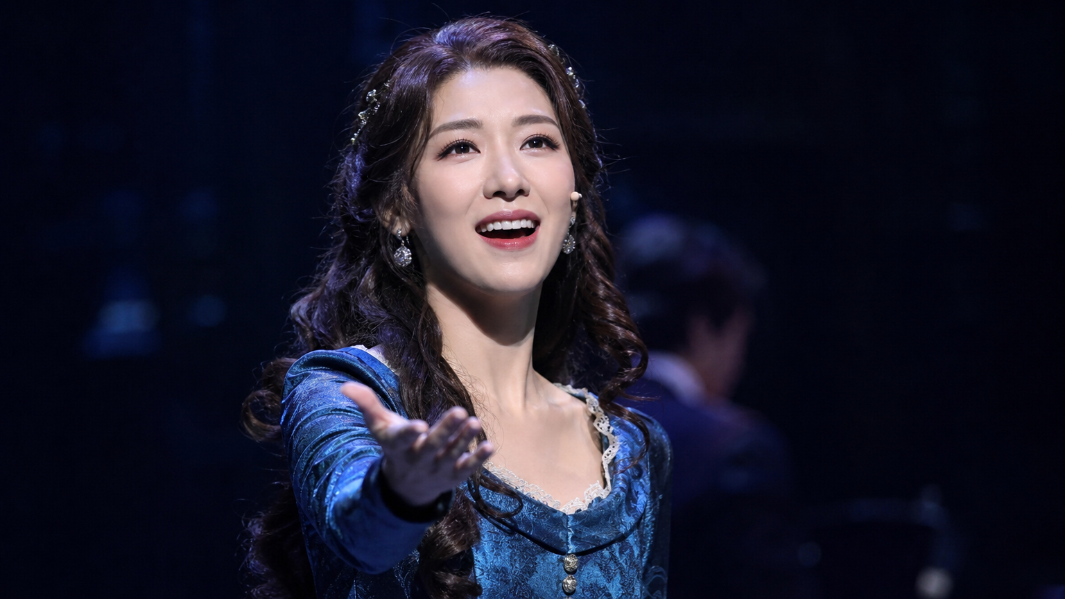 무대 위에서 화려한 의상을 입고 열정적으로 공연하는 뮤지컬 배우의 모습
