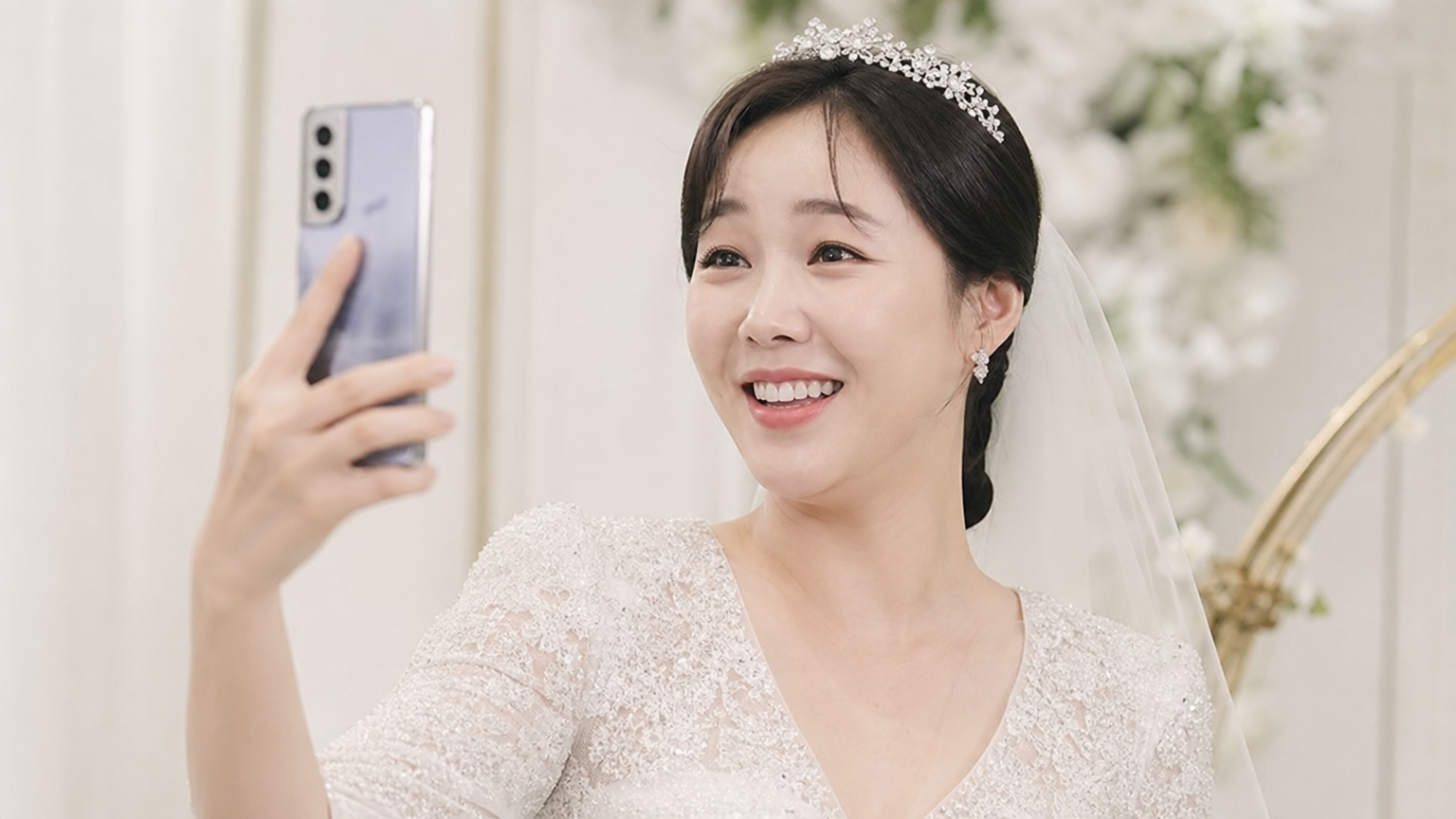 신부 드레스를 입고 스마트폰을 들고 밝게 웃고 있는 여성 개그우먼