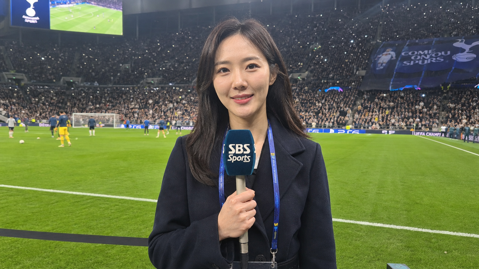 한국 스포츠 기자가 경기장에서 선수들과 팬들의 열정과 분위기를 포착하는 장면