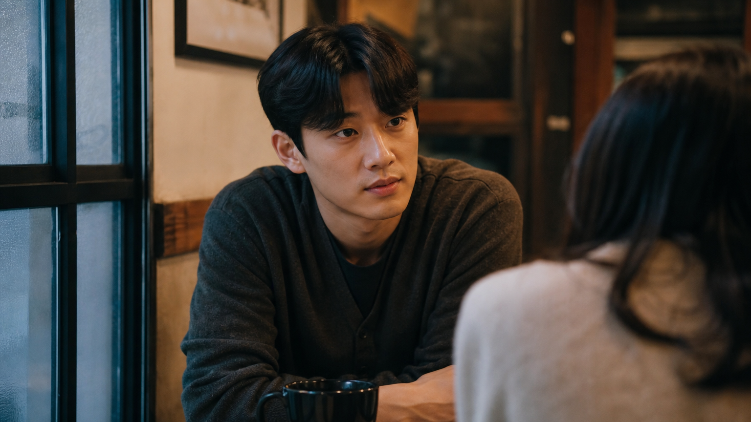 카페에서 생각에 잠긴 듯 상대방을 바라보는 남성