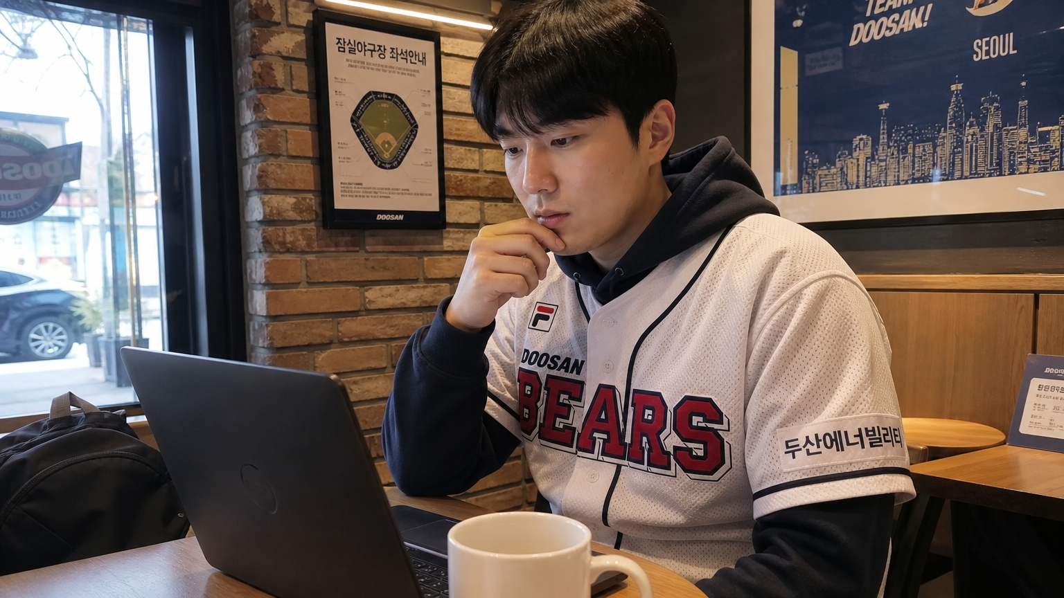 두산 베어스 유니폼을 입고 카페에서 노트북으로 KBO 리그 분석을 읽고 있는 현대적인 야구 팬