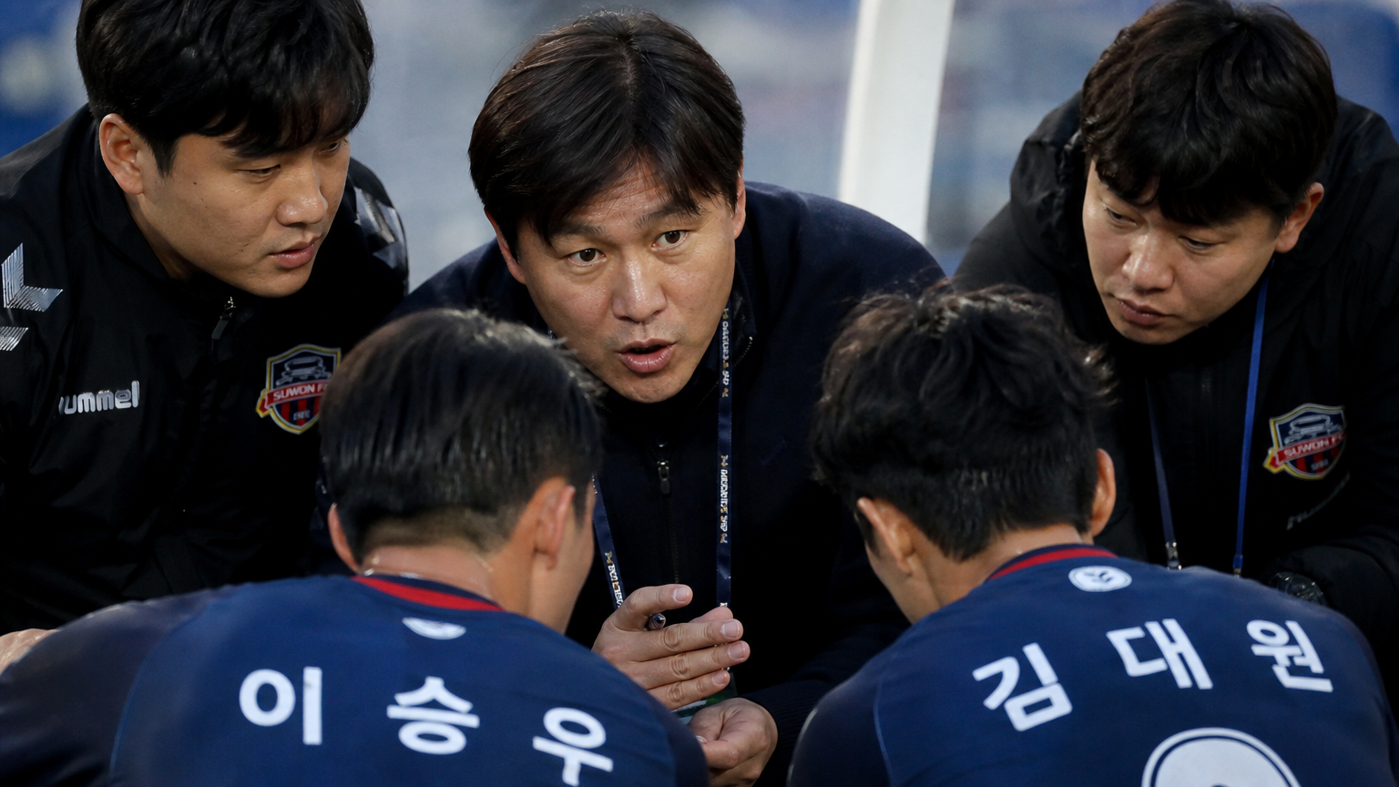 한국 축구 감독이 경기 중 작전을 설명하며 집중하는 장면