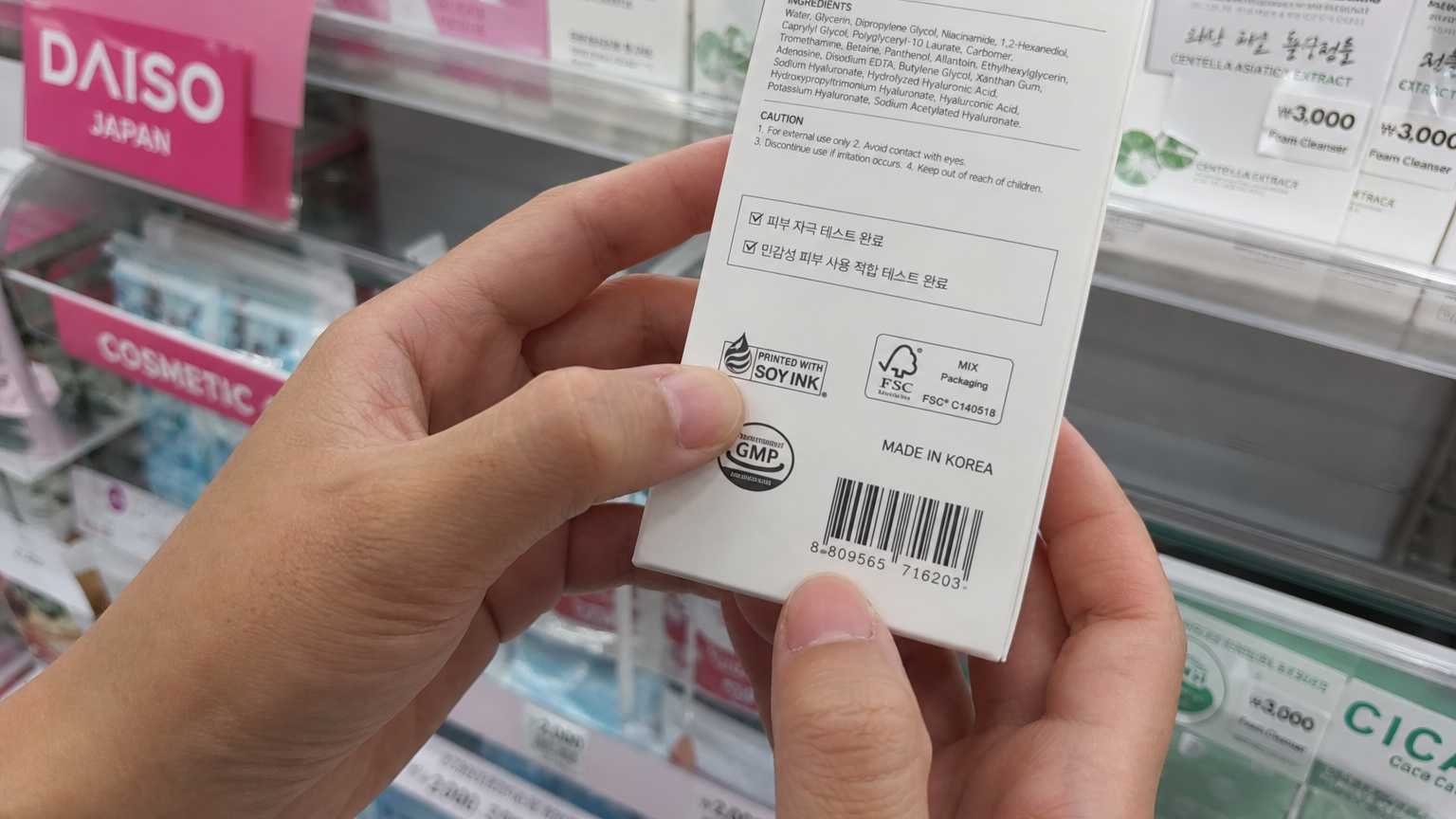 화장품 라벨에서 안전 인증 마크를 꼼꼼히 확인하는 손 모습