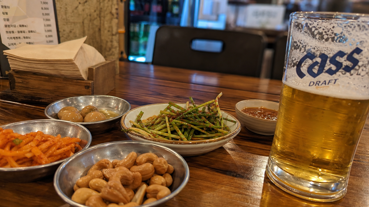 작은 안주와 맥주 한 잔이 놓인 테이블의 근접 사진
