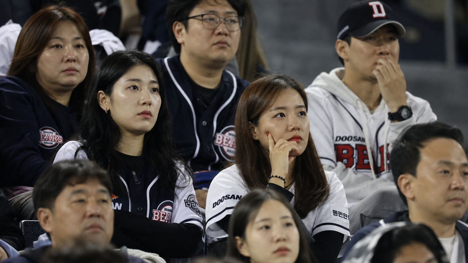 야구 경기장에서 경기를 관람하며 아쉬운 표정을 짓고 있는 팬들