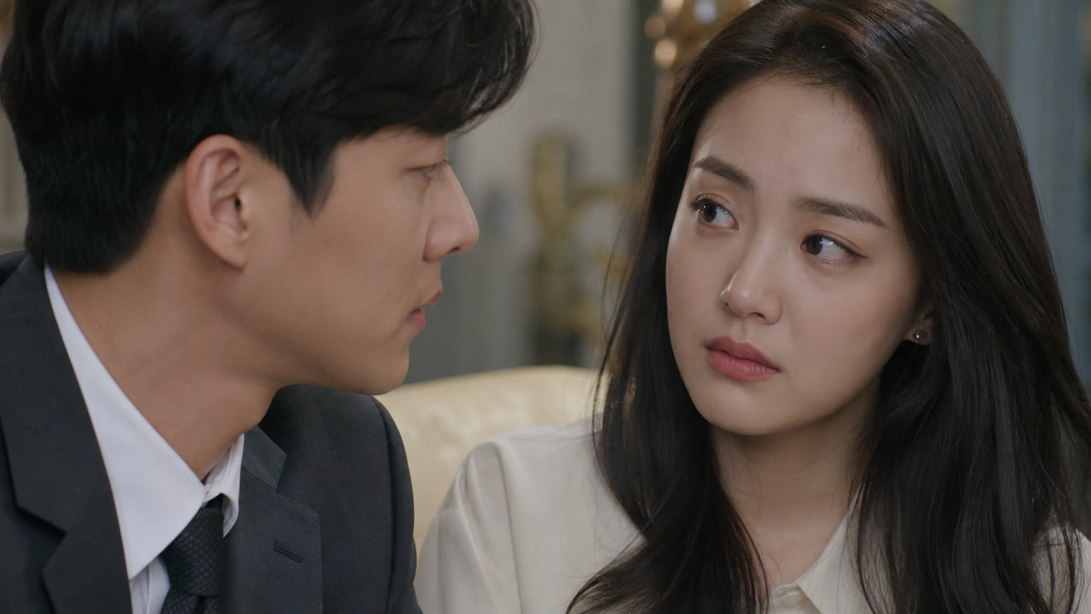 세련된 거실에서 대화를 나누며 미묘한 감정 변화를 보이는 남녀