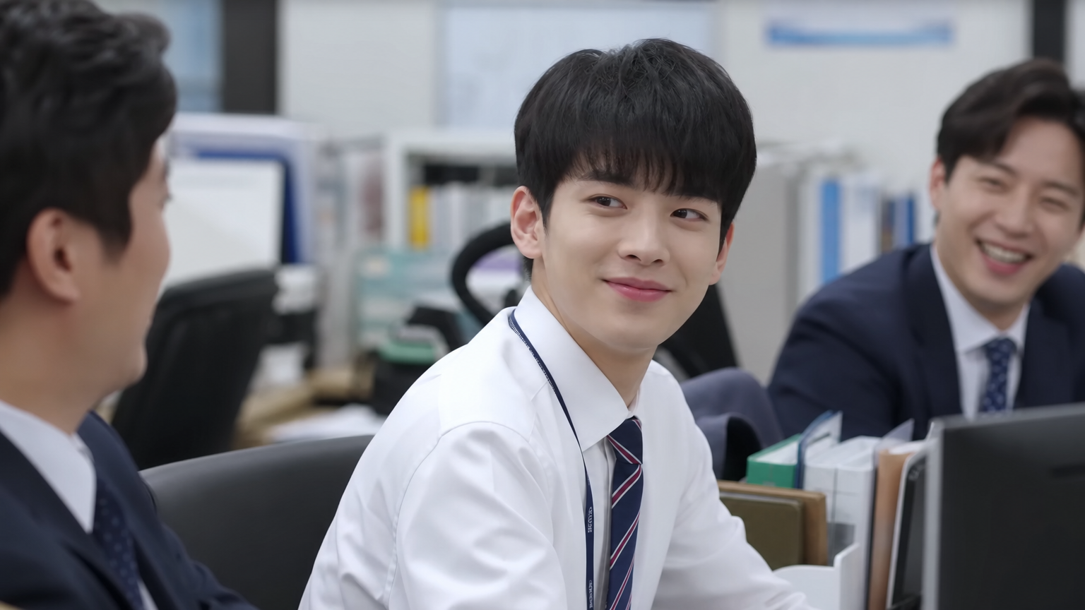 사무실에서 동료들과 함께 웃고 있는 사랑스러운 인턴 캐릭터의 드라마 장면