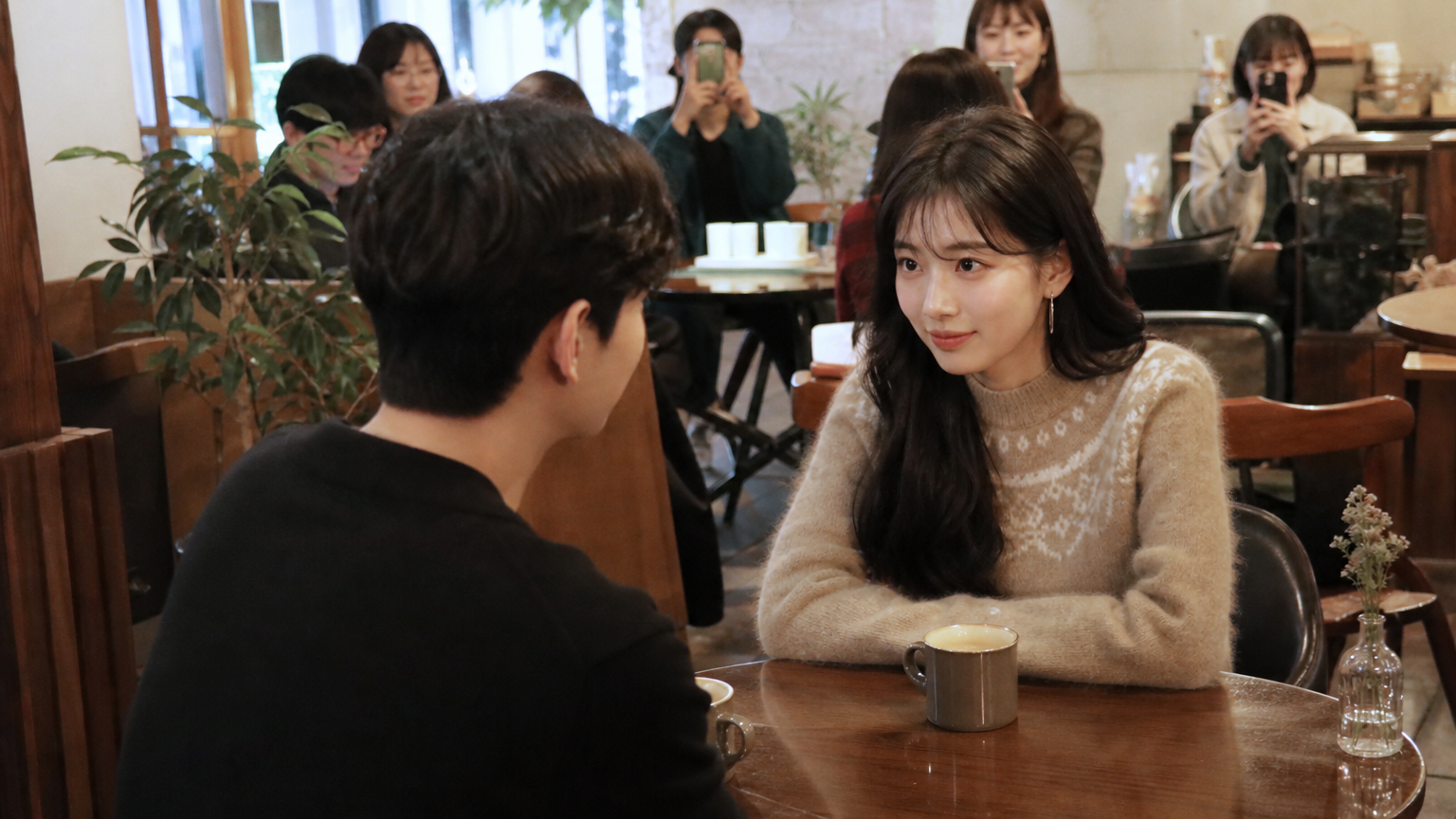 카페 테이블에서 커피를 마시며 대화 중인 두 명의 한국 유명인