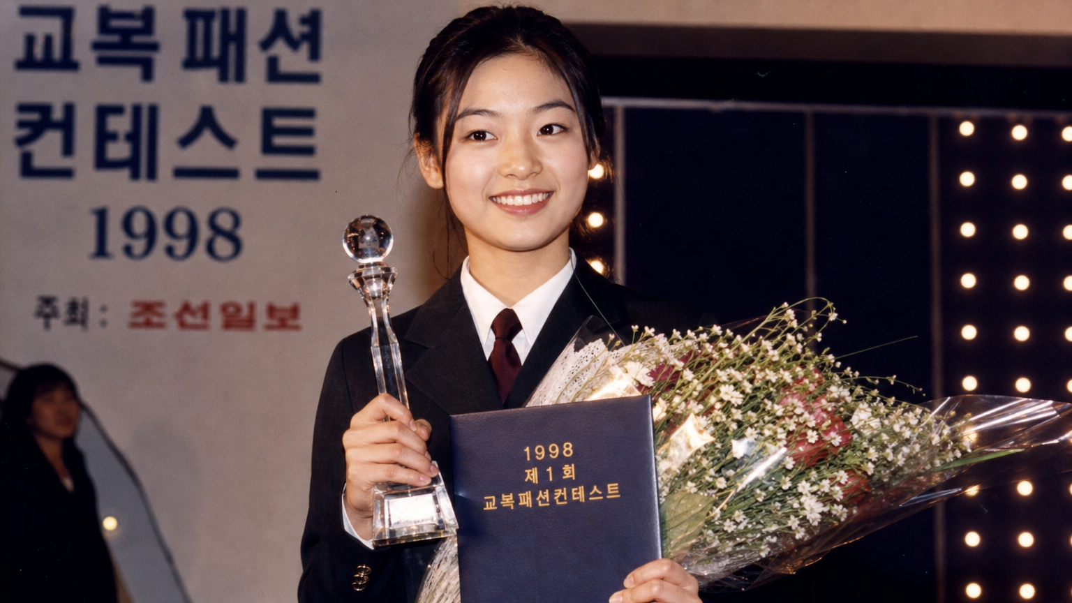 교복을 입고 자신감 넘치는 미소로 패션 콘테스트에서 우승하는 십대 소녀